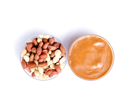 Peanut butter isolated and peanuts in the peel scattered on the white background. Copy space
