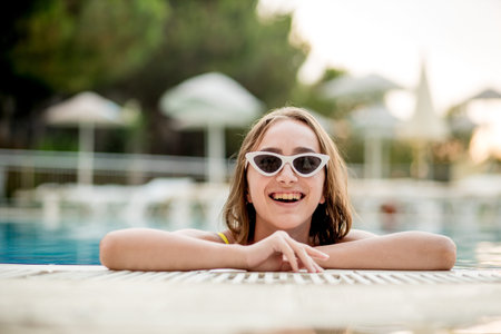 Beautiful woman in a hat and sunglasses relaxing in the pool.
