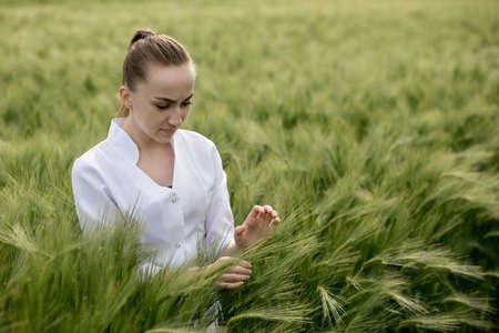 Ecologist in a white coat and glasses examining plants.の写真素材