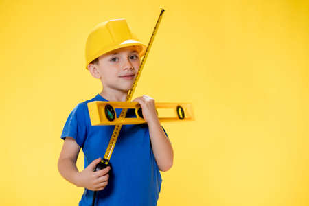 Little boy in yellow helmet builder with level toolの写真素材
