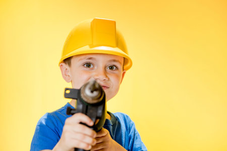 Smiling boy builder in a blue shirt holding a drill