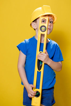 The preschooler holds a construction level in his hands, dreams of becoming a builder.