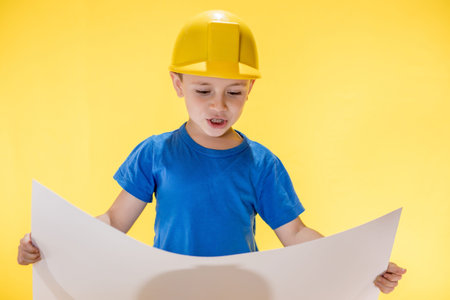 A little boy holding plan project in his hands dreams of becoming a famous architect.