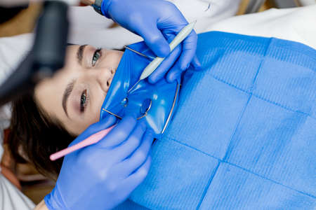 A dentist treats a woman's teeth using a cofferdam. dental equipment.の写真素材