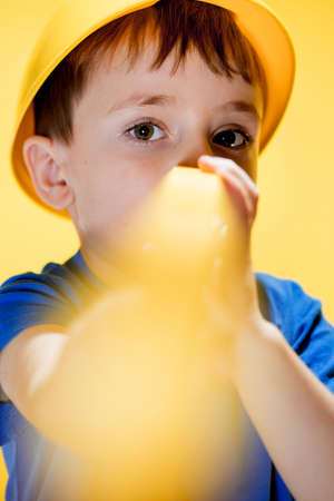 The preschooler in a helmet with a construction level plays a builder.の写真素材
