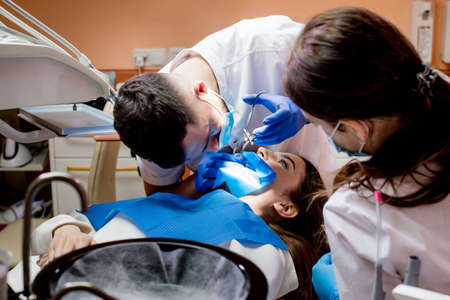 A dentist treats a woman's teeth using a cofferdam. dental equipment.の写真素材