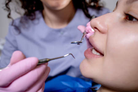 Health check. Dentist in stomatology center is making an examination of woman teeth by using dental toolsの写真素材