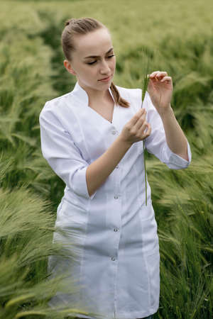 Ecologist or biologist in a white coat and glasses examining plants.の写真素材