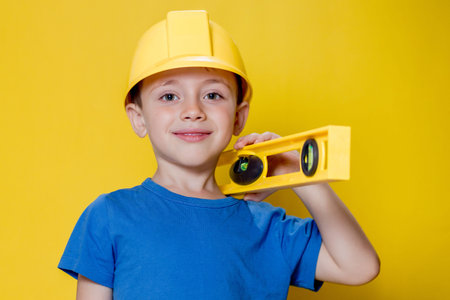 The preschooler in a helmet with a construction level plays a builder.