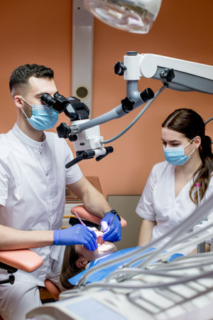 Dentist looking through a microscope at the patient's teeth. Modern progressive dentistryの写真素材