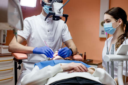 Dentist looking through a microscope at the patients teeth. Modern progressive dentistry.の写真素材