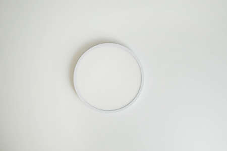 Round, minimalist, simple lamp on a white ceiling. A lamp that does not attract attentionの写真素材