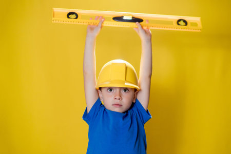 The preschooler holds a construction level in his hands, dreams of becoming a builder.の写真素材