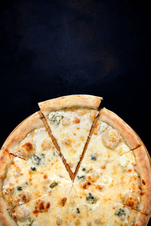 Pizza with four cheeses, mozzarella, blue cheese, Parmesan cheese. Italian cuisine on black background. View from aboveの写真素材