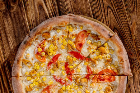 Pizza for children on a cream base with chicken fillet, tomatoes, corn and mozzarella cheese on wood background.の写真素材
