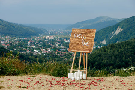 A romantic location in the mountains for a proposal of the hand and the heart Wooden easel with the inscription marry me. mountain landscape.の写真素材