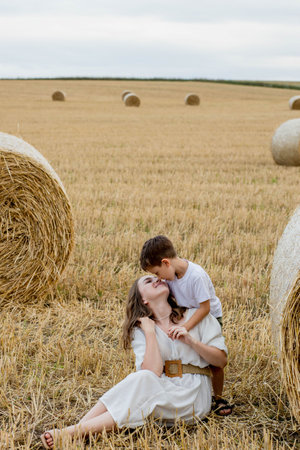 Young mother and her son are hugging near straw bales in a field. A happy family. mother's day.の写真素材