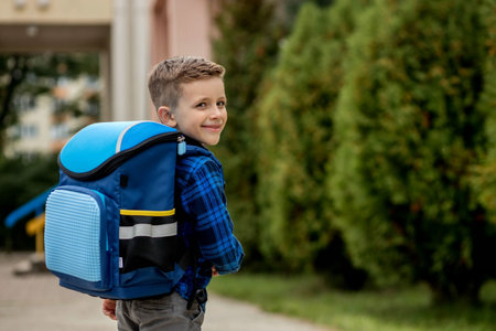Portrait of a schoolboy in a blue shirt with a backpack and textbooks. little schoolboy. First grader.の写真素材