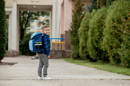 Portrait of a schoolboy in a blue shirt with a backpack and textbooks. little schoolboy. First grader.の写真素材