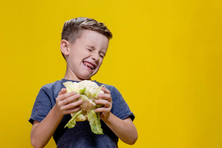 A charming little boy refusing to eat cauliflower. Health food.の写真素材