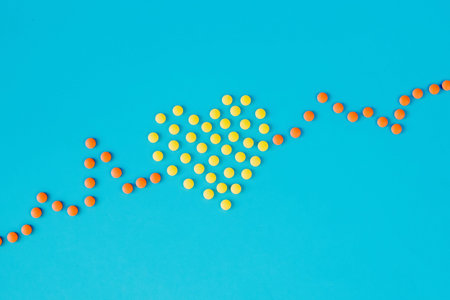 Medical pills in the shape of a heart and cardiogram, capsules on a blue background. heart disease.