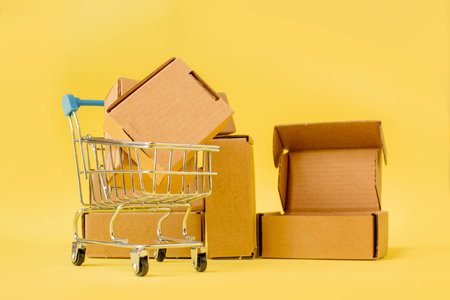 Shopping cart with boxes on a yellow background. The concept of sales, discounts, online shopping and deliveryの写真素材