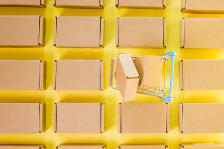 Shopping cart with boxes on a yellow background. The concept of sales, discounts, online shopping and deliveryの写真素材