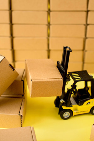 Warehouse with cardboard kraft boxes and a forklift truck. Cargo sorting concept.の写真素材