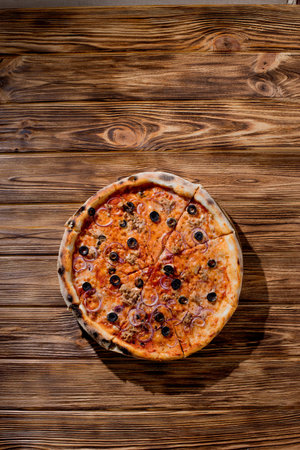 Pizza with tuna, olives, onions, mozzarella cheese and tomato sauce on wood background. Top view, copy space.の写真素材