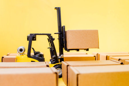 Forklift truck raises cardboard boxes on a yellow background. Cargo sorting concept.