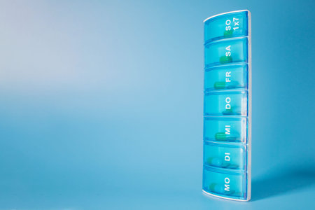Plastic container with various pills on a blue background. Planning the use of tablets.の写真素材