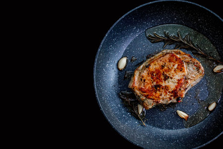 Chef cooking juicy beef meat on frying pan with rosemary and garlic, uses kitchen utensils. Process of roasted steak cookingの写真素材