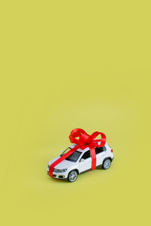 White model car with bow on a yellow background. Car as gift, surprise.の写真素材