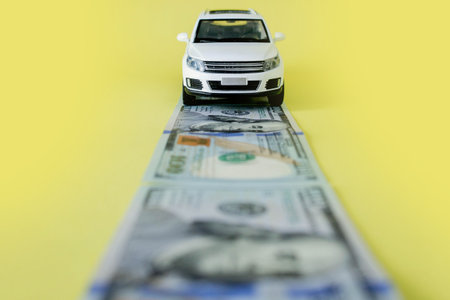 White toy car on money road on yellow backgroundの写真素材