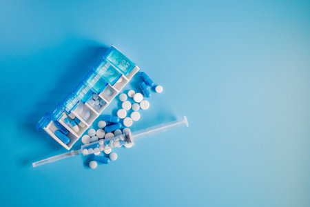 Top view of weekly pill box organizer, portable travel prescription or medication pill case on blue background. Health care and medical conceptの写真素材