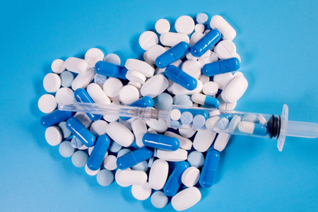 White pills and blue capsules in the shape of a heart on a blue background. Pills for heart healthの写真素材