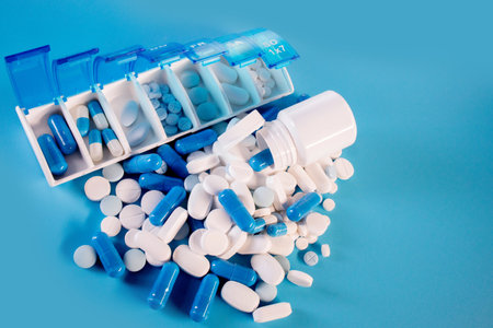 Blue-white pills and capsules in weekly pill organizer.の写真素材