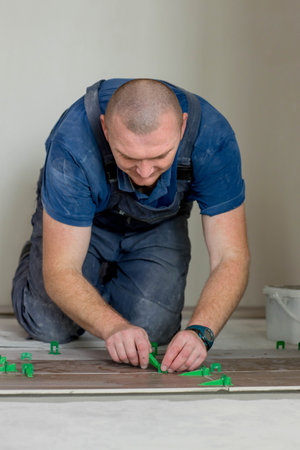 Tiler put clips in lash tile leveling system on the floor in a new house.の写真素材