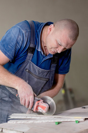 Professional tiler cutting ceramic tile for the floor or wall. Flooring and tiling