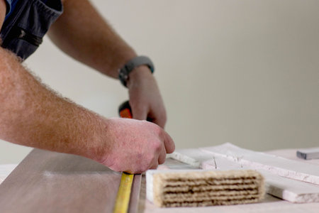 Professional tiler measuring and sticking with tape for cutting ceramic tiles for installing floor....