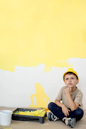 Home repairs. Cute boy with a paint roller. Happy kid helps parents to paint wall. New house renovation conceptの写真素材