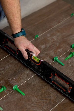 Close up hands of repairman laying tiles with tile leveling system on the floor in a new house