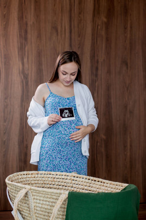 A pregnant woman looks at the ultrasound photo of her baby.の写真素材