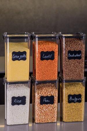 Storing groceries in polypropylene boxes according to the Konmari method in the kitchen. Placing, sorting, storing products in plastic boxes with a header in a Scandinavian kitchen style. General cleaning, tidying up.の写真素材