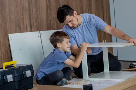 Father and son assemble new furniture on floor of new apartment, concept of experience and trainingの写真素材