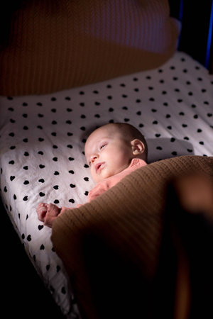 Cute little baby sleeping in cradle at home night.の写真素材