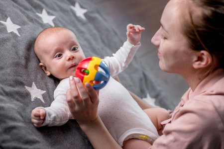 Young mother talks and plays with her baby son while lying on her back. Baby care, motherhood concept.の写真素材