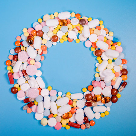 Frame with colorful pills and capsules on a blue background. Place for text.