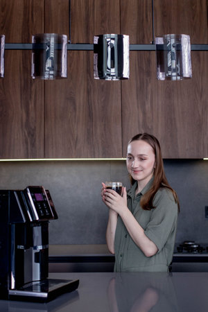 Female enjoying of fresh coffee aroma after brewing coffee using coffee maker in the kitchen at homeの写真素材