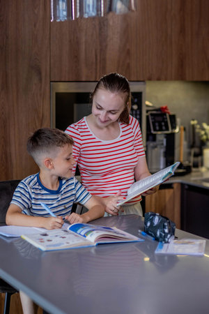 Mother helping her son doing homework in kitchen.の写真素材